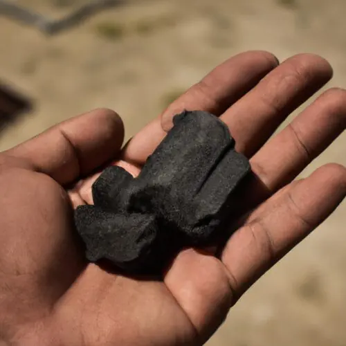 A person holding a piece of charcoal in his hand