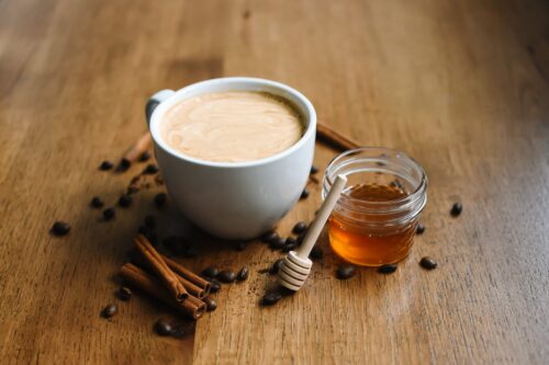 photo of a cup of coffee beside a jar of honey
