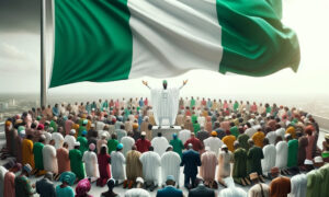 Nigerian flag flying high with a group of diverse people beneath it kneeling down and praying with closed eyes
