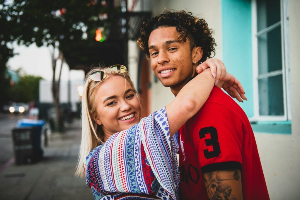 200+ Questions To Ask Your Boyfriend On Valentine's Day 5 smiling woman with both hands wrap around man's neck near white concrete building